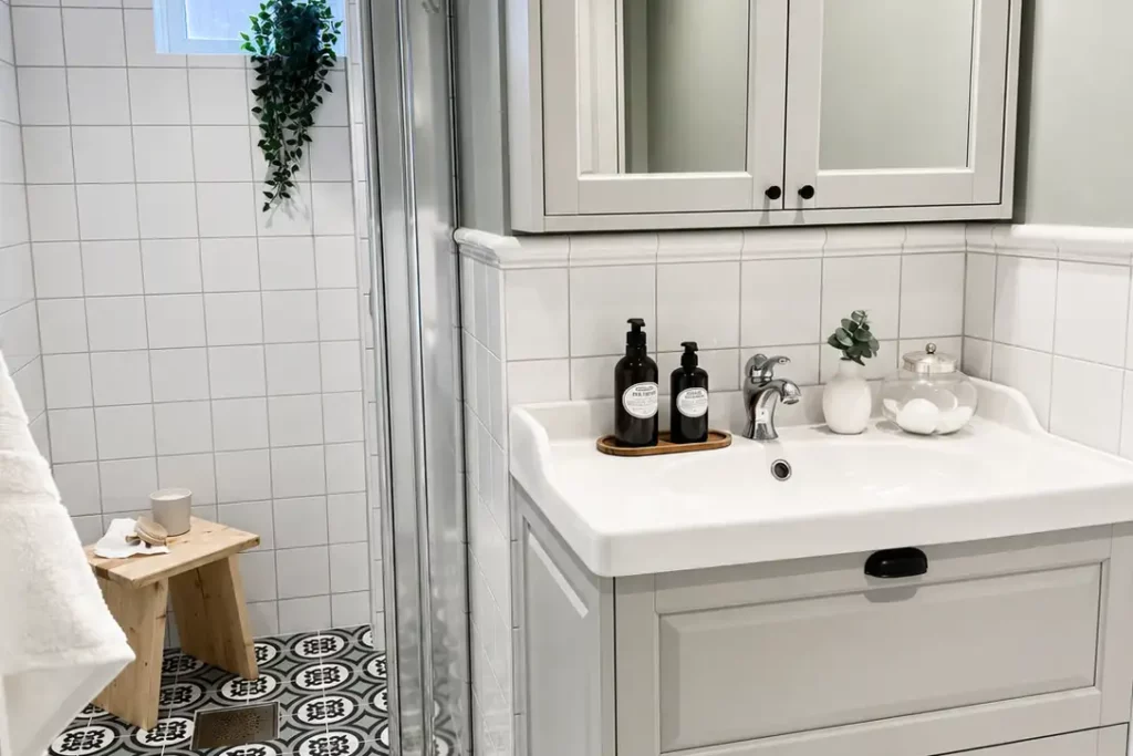 Badrum i Nacka med dusch, kommod, spegel och mönstrat klinkergolv renoverat av Renovera Nu.